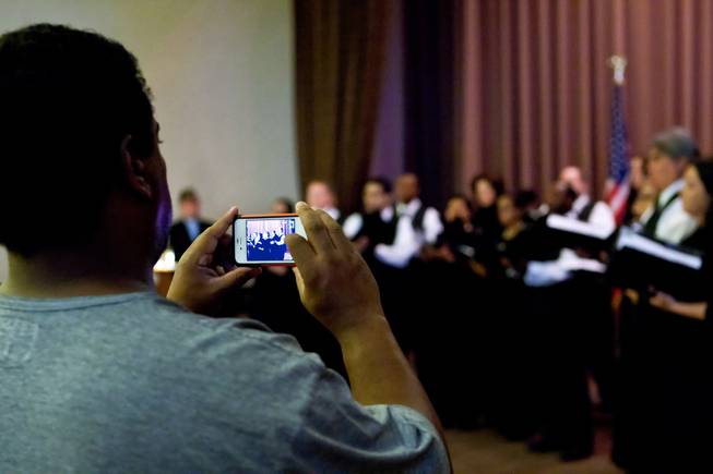 A guest shoots a video of the Las Vegas Master Singers Chamber Chorale perform during the 48th Annual Memorial Day Service at the Palm Downtown Mortuary and Cemetery in Las Vegas, Monday, May 27, 2013.